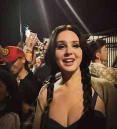 a woman with long braids standing in front of a group of people holding cell phones