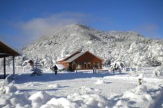 a cabin in the middle of a snowy mountain range with snow piled up around it