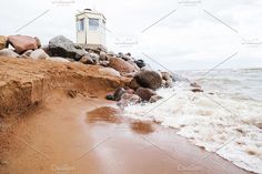 the beach is covered in waves and rocks, with a small hut on top of it