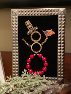 a photo frame with a red beaded bracelet and an american flag pin on it