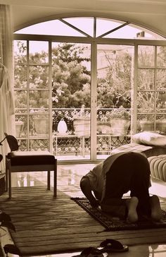 a man kneeling on top of a rug in front of a window