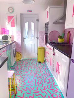 a brightly colored kitchen with white cabinets and black counter tops is pictured in this image