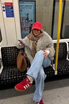 a woman sitting on a subway train with her legs crossed and holding a purse in one hand