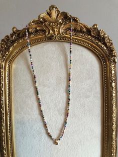 a gold frame with a beaded necklace hanging from it