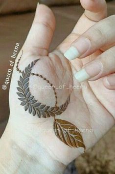 a woman's hand with a hendi on it and a leaf tattoo on the wrist