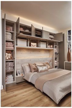 a large bed sitting under a window next to a wooden shelf filled with folded towels