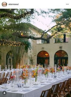 a long table is set up with clear vases and candles for an outdoor wedding reception