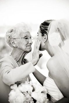 an older woman is touching the bride's face