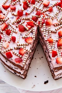 a cake with strawberries on top is cut into pieces and sits on a plate