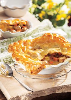 a pie sitting on top of a wooden table next to two bowls filled with food