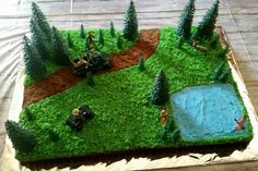 a cake that is shaped like a field with trees and people on the grass in it