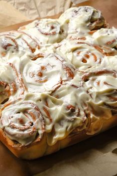 a cinnamon roll sitting on top of a piece of wax paper covered in icing