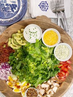 a wooden plate topped with lots of different types of food next to silverware and utensils