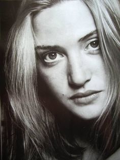 a black and white photo of a woman's face with long blonde hair, looking directly into the camera