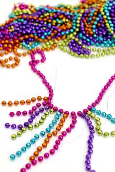 the beads are being sewn together to make a beaded necklace with colored beads