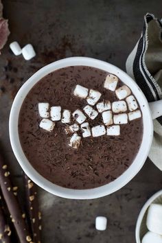 a white bowl filled with hot chocolate and marshmallows on top of a table