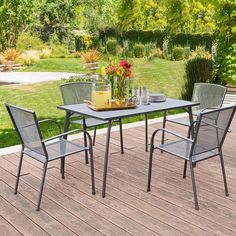 an outdoor table and chairs on a deck with flowers in the vase, water bottle and glasses