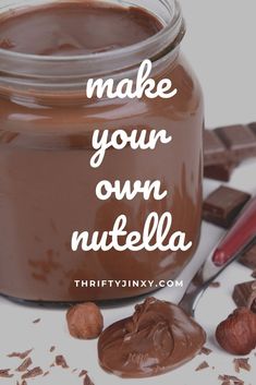 a jar filled with chocolate and nuts on top of a white table next to a spoon