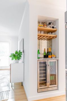 an open refrigerator in a kitchen next to a counter with bottles and glasses on it