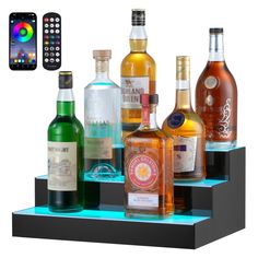 there are many different types of alcohol on the shelf with remotes next to it