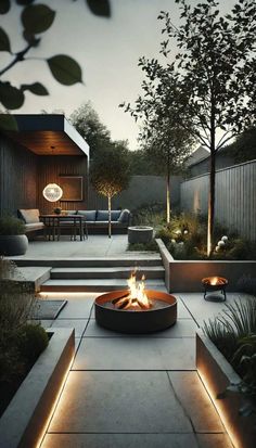 an outdoor fire pit surrounded by concrete steps and trees with lights on it at night