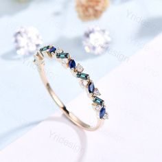 a diamond and blue sapphire ring on a table with other jewelry items in the background