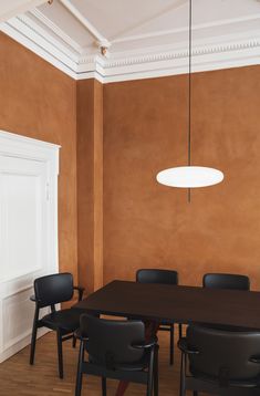 a dining room table and chairs in front of an orange wall with white moldings