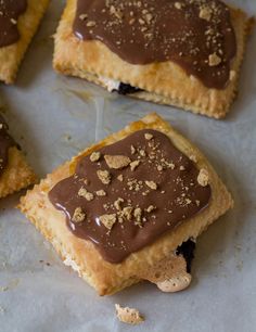 four pieces of dessert sitting on top of a piece of parchment paper with chocolate frosting