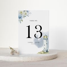 a table number card with a lighthouse and flowers on the top, next to it