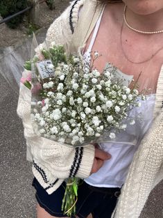 a woman holding a bouquet of white flowers