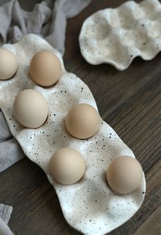 six eggs in an egg carton on a wooden table with napkins around them