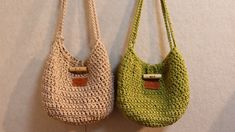 two crocheted purses hanging on a wall next to each other, one green and the other beige