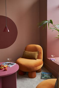 a red living room with a deep red cycle painted on the wall, there is a orange chair and a pink coffee table with cocktails on it 70s Nostalgia, Back In Time, Jewel Tones, Persian, Velvet, Feelings