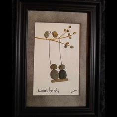 two birds sitting on a tree branch with leaves and rocks in the shape of hearts