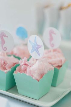 cupcakes with pink frosting and seahorse toppers on a green tray