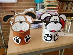 two paper cups with dogs on them sitting on a table in front of a bookshelf