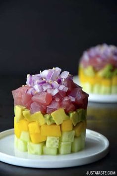 two small cakes with different types of toppings on top of each other, sitting on white plates