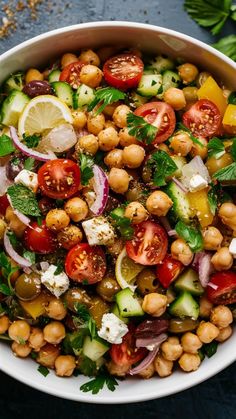 a salad with chickpeas, tomatoes, cucumbers and herbs