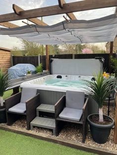 an outdoor hot tub surrounded by potted plants and chairs with a covered patio area in the background