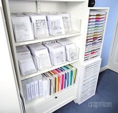 a white bookcase filled with lots of books next to a wall mounted shelf full of files