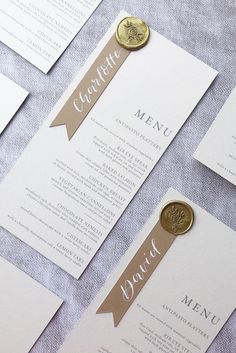 wedding menu cards with wax stamp and gold seal on grey linen tablecloth, closeup