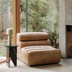 a living room with a couch, table and glass doors that look out onto the woods