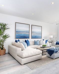 a living room filled with white furniture and blue pillows on top of it's couches