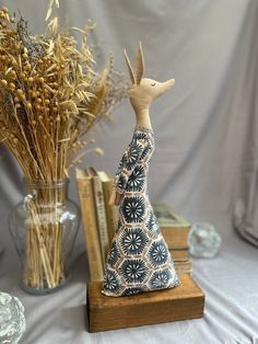 a wooden figurine sitting on top of a table next to books and vases