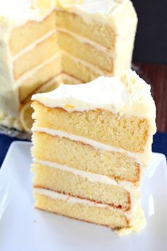 a slice of white cake on a plate with the rest of the cake in the background