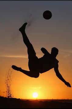 a person jumping up into the air to catch a frisbee in front of a sunset