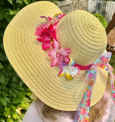 "Who's ready for the beach?  Do you have all the appropriate beach gear you'll need when summer rolls around?  How about a fun beach hat, more specifically, a fun beach hat that reminds you of being at a tropical island?  This woven straw sun hats has a wide, floppy brim and 22\" circumference to fit nearly all adults.  The sun hat is breathable and keeps the sun's glare at bay, making it perfectly comfortable to wear outdoors in the summer, gardening or hosting backyard parties. Use the floppy sun hat as table decor that guests can take with them!  Relax in style this summer by protecting your skin and looking fabulous.  An orchid-print and rainbow lace ribbons, bow and tropical orchids adding a wonderful touch! Start getting yourself beach ready with this adult floppy beach hat!" Tropical Hats Women, Adjustable Sun Hat For Poolside, Pink Sun Hat With Uv Protection For Vacation, Sun Hats For Pool And Beach Season, Vacation Sun Hat With Uv Protection For Poolside, Beachwear Straw Hat With Uv Protection For Pool, Summer Straw Hat With Uv Protection For Sunbathing, Pink Summer Hat For Poolside, Beachwear Sun Hat For Pool Vacation