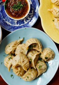 some dumplings are on a blue and white plate next to other plates with food