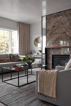 a living room filled with furniture and a fire place in front of a stone wall