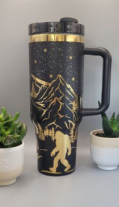 a black and gold travel mug next to some succulents